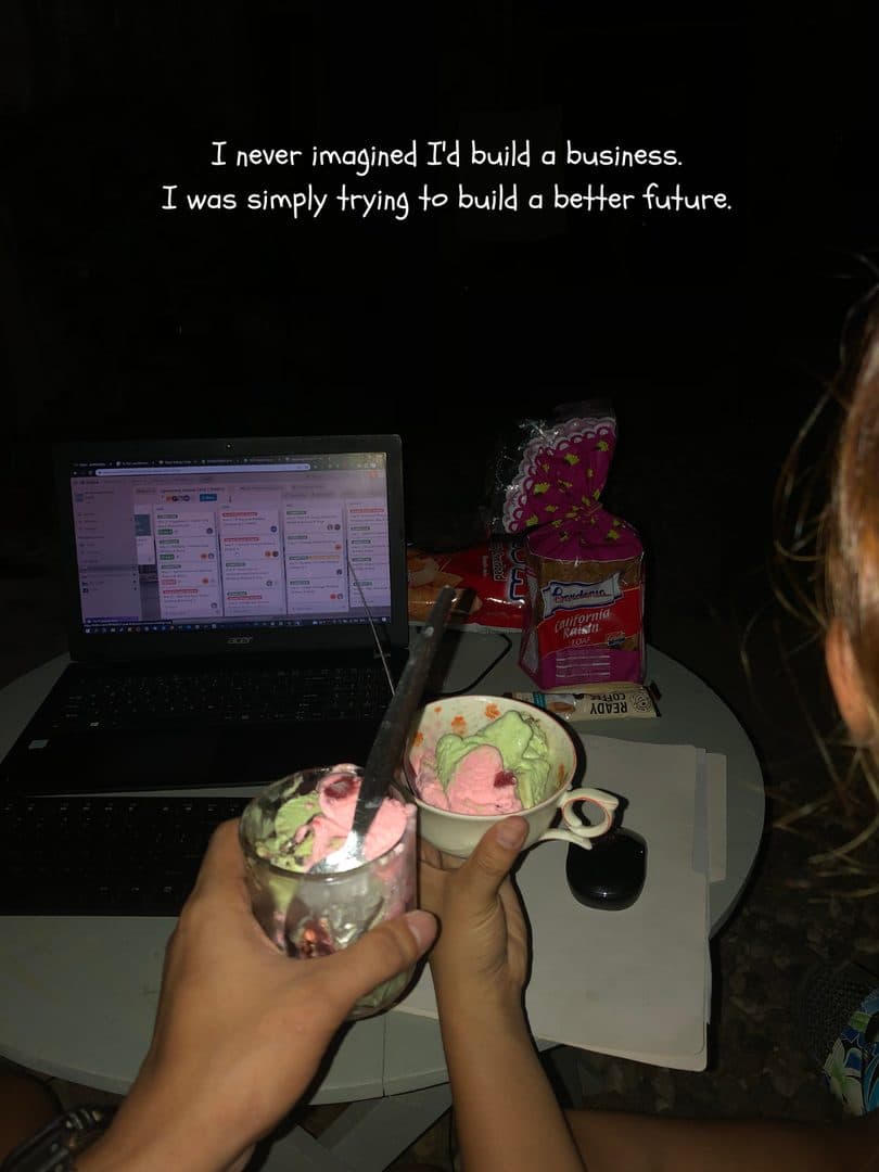 Two bowls of ice cream held up in front of a laptop, working late