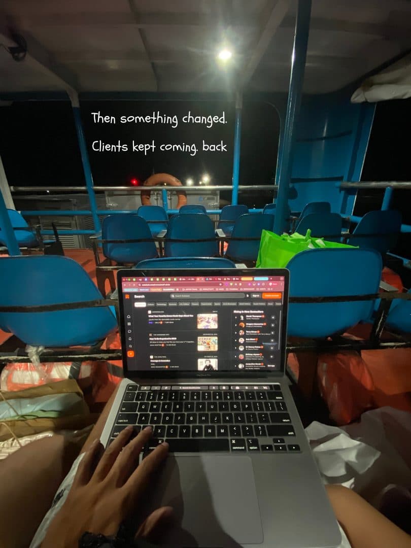 A laptop balanced on a lap, working from a row of blue chairs
